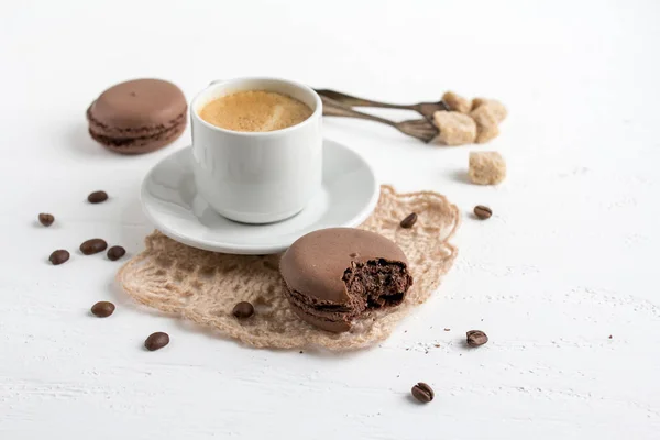 Taza de café y macarrones franceses de chocolate en una espalda de madera blanca — Foto de Stock