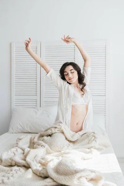 Mujer despertando estirándose en la cama por la mañana —  Fotos de Stock