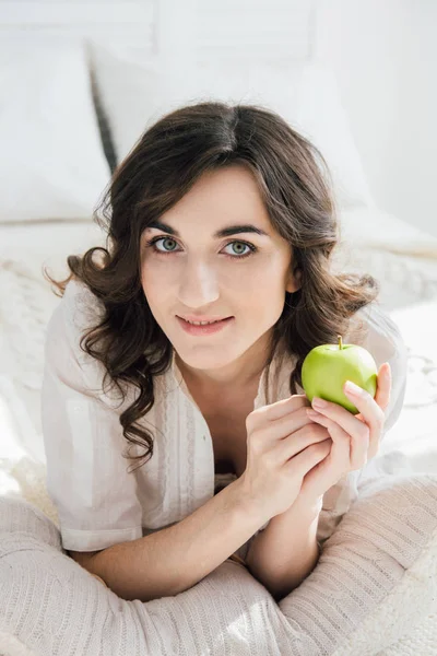 Bella ragazza sdraiata a letto e con in mano una mela — Foto Stock