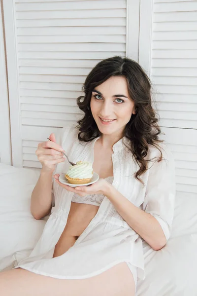 Chica come pastel para el desayuno en la cama — Foto de Stock