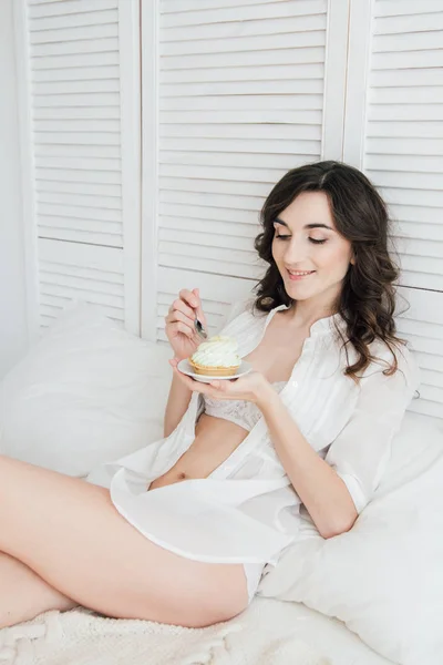 Chica come pastel para el desayuno en la cama — Foto de Stock