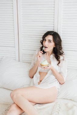 Kız yatakta kahvaltı için kek yiyor 