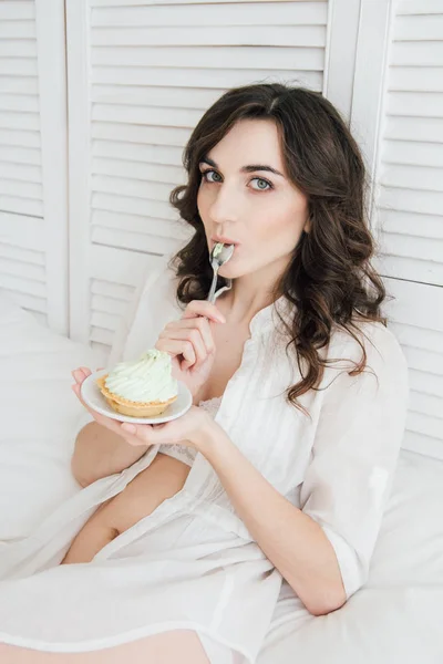 Gadis makan kue untuk sarapan di tempat tidur — Stok Foto