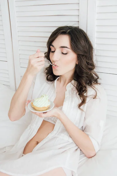 Девушка ест торт на завтрак в постель — стоковое фото