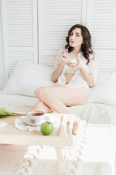 Dziewczyna zjada ciastko na śniadanie w łóżku — Zdjęcie stockowe