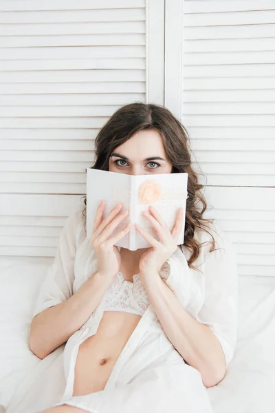 Chica escribe en un cuaderno en la cama — Foto de Stock