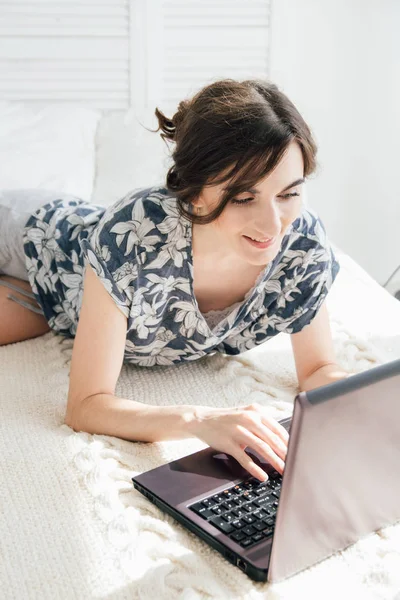 Девушка смотрит на ноутбук на кровати — стоковое фото