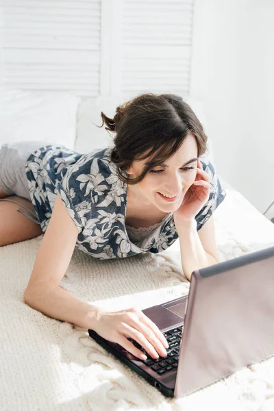 Meisje kijkend naar de laptop op het bed — Stockfoto