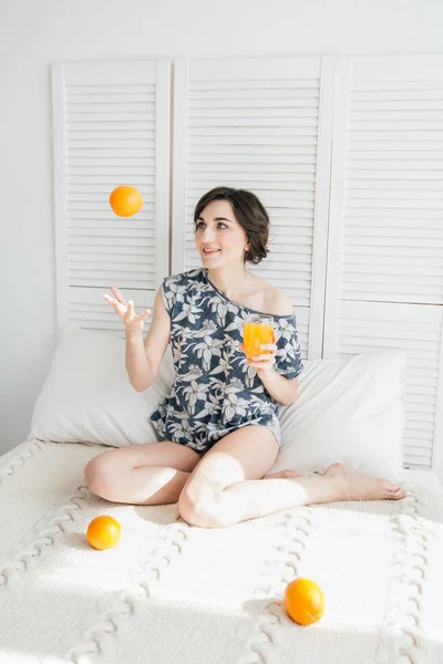 Chica bebiendo jugo de naranja en el desayuno en la cama — Foto de Stock