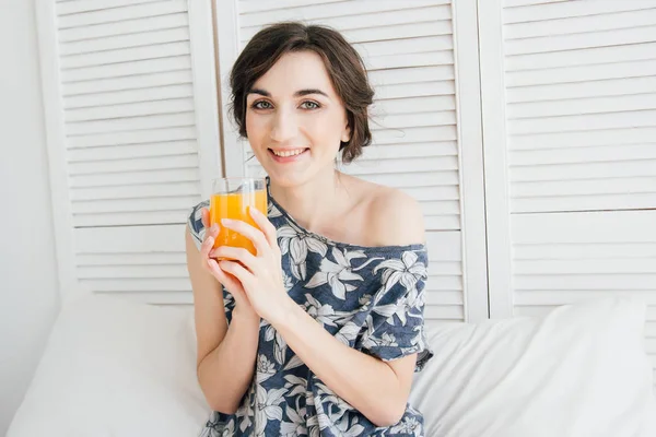 Dziewczyna pije sok pomarańczowy na śniadanie w łóżku — Zdjęcie stockowe