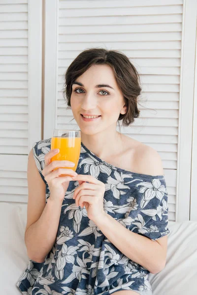 Chica bebiendo jugo de naranja en el desayuno en la cama — Foto de Stock