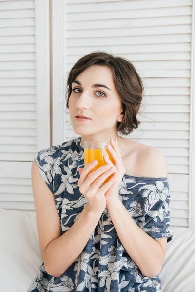 Chica bebiendo jugo de naranja en el desayuno en la cama — Foto de Stock