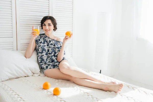 Gadis minum jus jeruk saat sarapan di tempat tidur — Stok Foto
