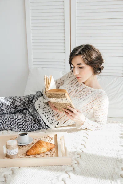 Девушка читает книгу за завтраком — стоковое фото