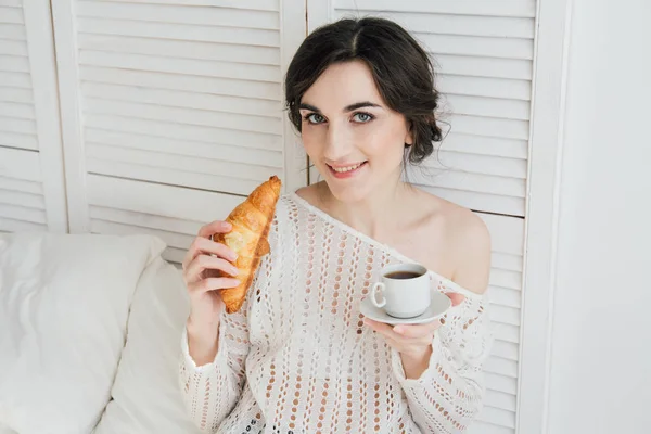 Fata bea cafea și un croissant în pat — Fotografie, imagine de stoc