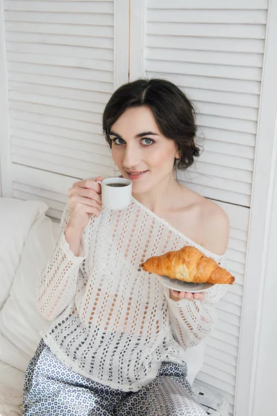 Девушка пьет кофе и круассан в постели — стоковое фото