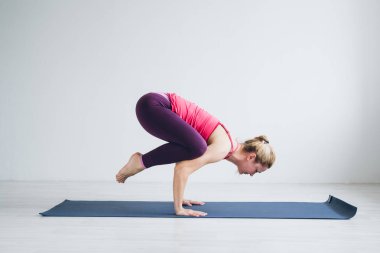 Beyaz yoga egzersizleri yapıyor bir odada genç kadın .