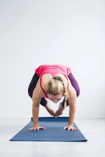 Mujer joven en una habitación blanca haciendo ejercicios de yoga  . — Foto de Stock