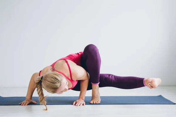 Wanita muda di ruangan putih melakukan latihan yoga  . — Stok Foto