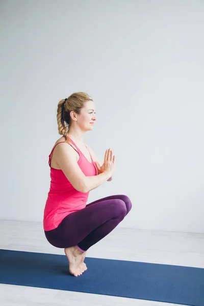 Mujer joven en una habitación blanca haciendo ejercicios de yoga  . — Foto de Stock