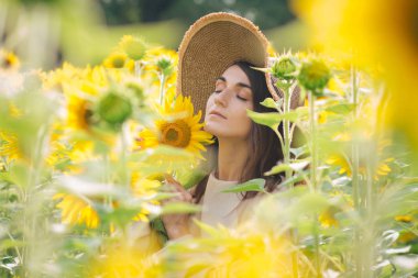 Ayçiçeği tarlası üzerinde şapkalı genç kız