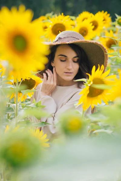 Junges Mädchen mit Hut auf einem Sonnenblumenfeld — Stockfoto