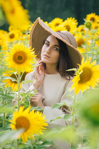 Junges Mädchen mit Hut auf einem Sonnenblumenfeld — Stockfoto