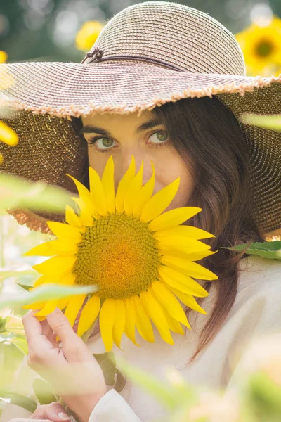 Junges Mädchen mit Hut auf einem Sonnenblumenfeld — Stockfoto