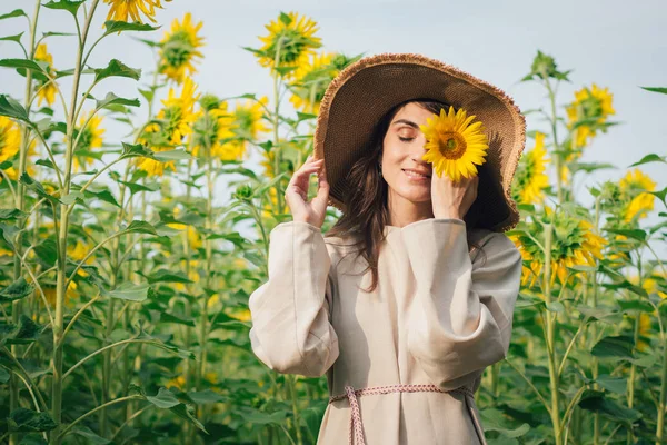 Junges Mädchen mit Hut auf einem Sonnenblumenfeld — Stockfoto