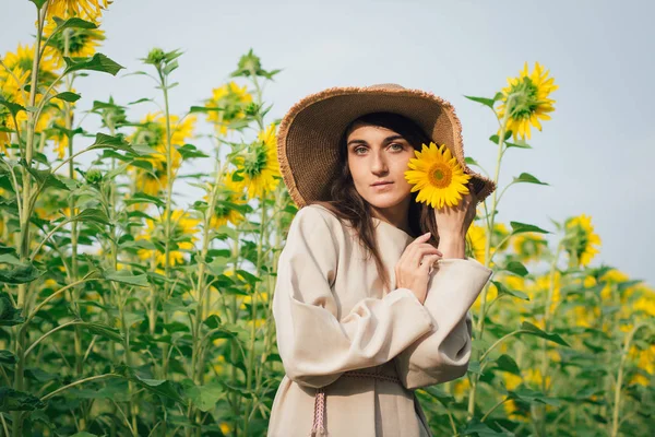 Junges Mädchen mit Hut auf einem Sonnenblumenfeld — Stockfoto