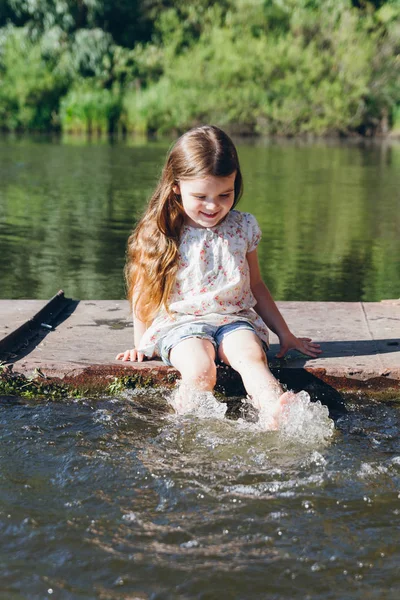Ragazzina immergendo i piedi in acqua e ridendo — Foto Stock