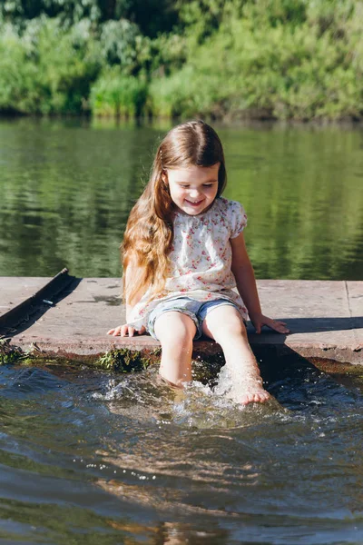 Ragazzina immergendo i piedi in acqua e ridendo — Foto Stock
