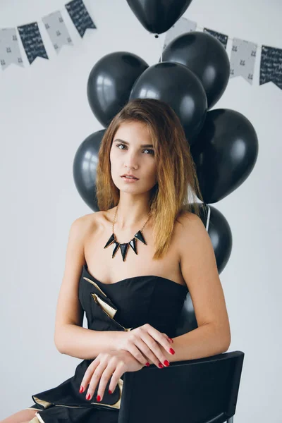 Chica en un vestido negro con globos negros — Foto de Stock