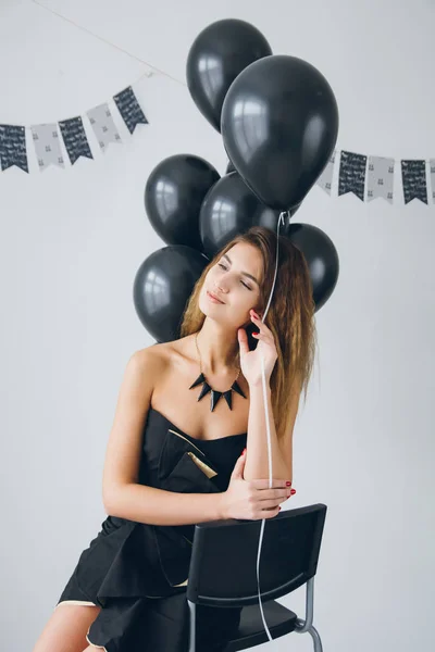 Menina em um vestido preto com balões pretos — Fotografia de Stock