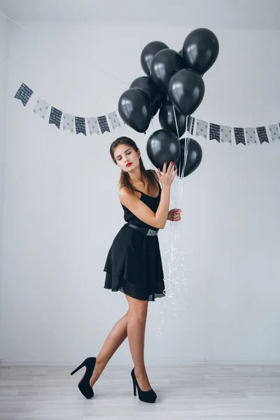 Menina em um vestido preto com balões pretos — Fotografia de Stock