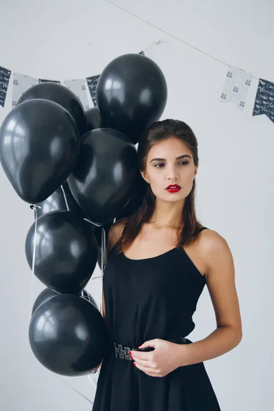 Menina em um vestido preto com balões pretos — Fotografia de Stock