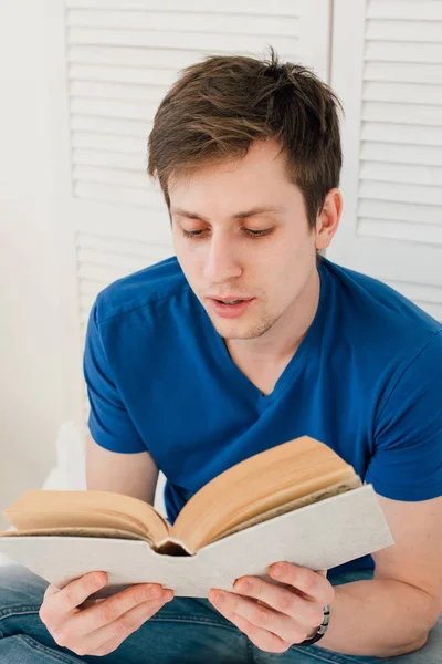 Homem lendo um livro sentado na cama — Fotografia de Stock