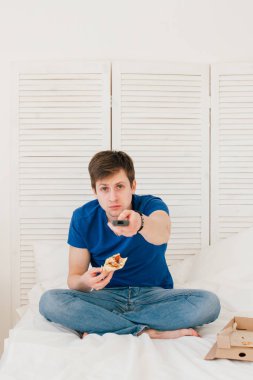 Yatakta oturmuş ve pizza yemek Tv izleyen adamım
