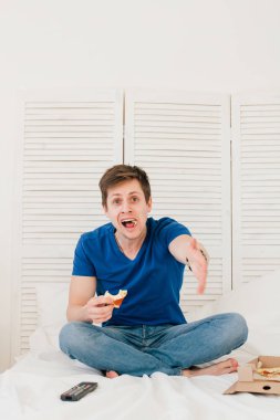 Yatakta oturmuş ve pizza yemek Tv izleyen adamım