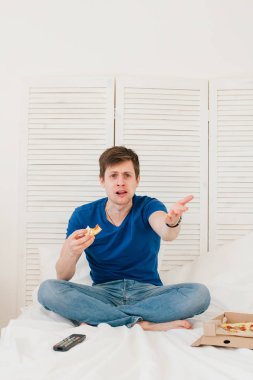 Yatakta oturmuş ve pizza yemek Tv izleyen adamım