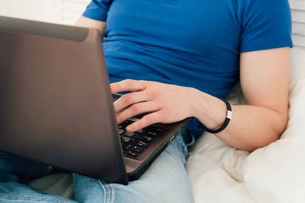 Ember dolgozik a laptop, ül az ágyon — Stock Fotó