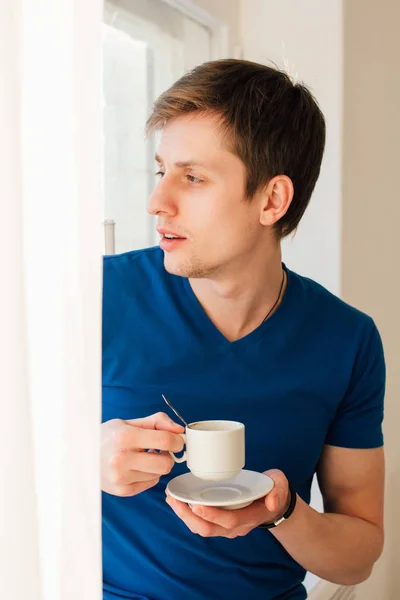 Человек пьет кофе, глядя в окно. — стоковое фото