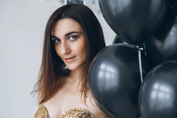 Girl in a gold dress with black balloons — Stock Photo, Image