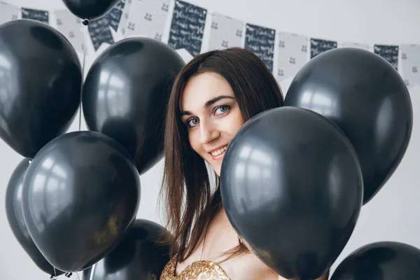 Menina em um vestido de ouro com balões pretos — Fotografia de Stock