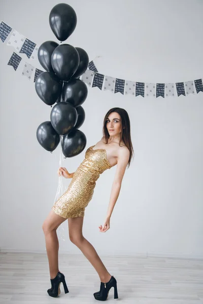 Meisje in een gouden jurk met zwarte ballonnen — Stockfoto