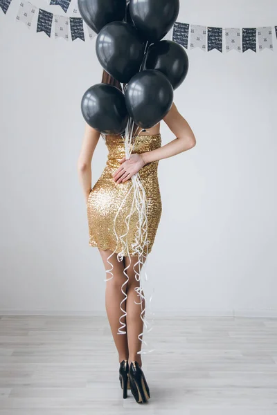 Menina em um vestido de ouro com balões pretos — Fotografia de Stock