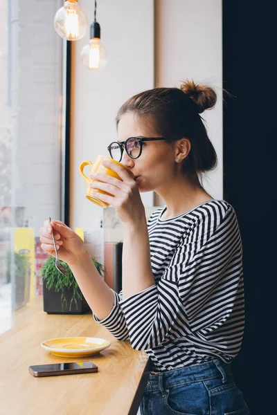 Girl in glasses drinking coffee