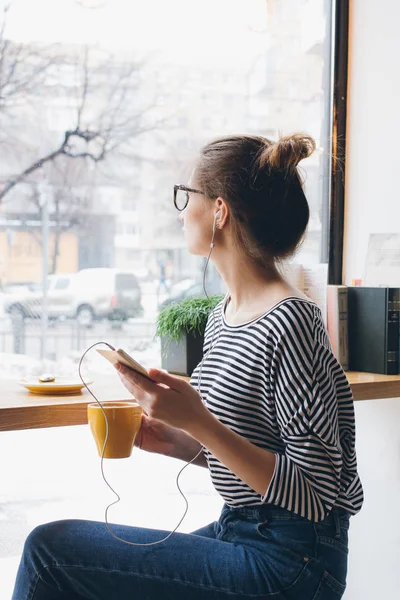 Девушка слушает музыку на вашем смартфоне и пьет кофе — стоковое фото