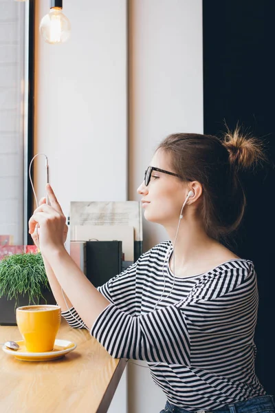 Девушка делает селфи на смартфоне в кофейне — стоковое фото