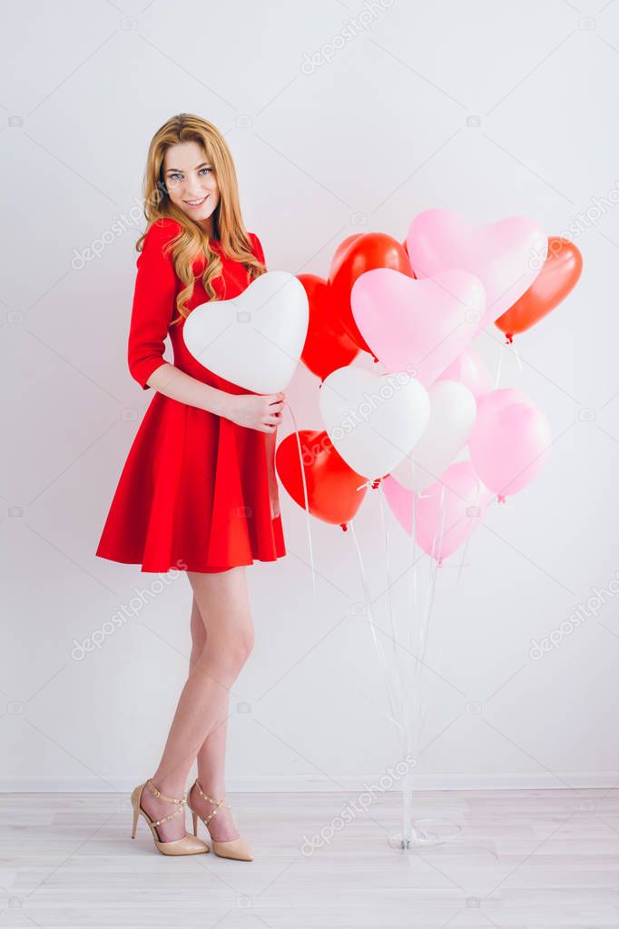 Girl in red dress with balloons in the shape of a heart